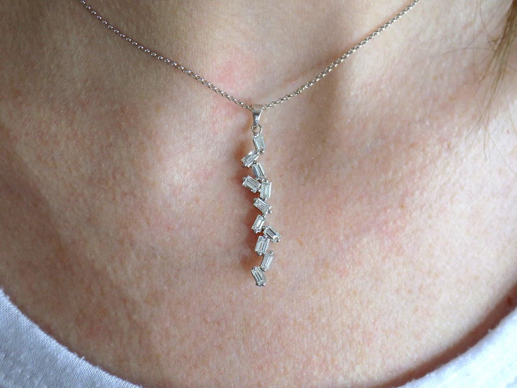 This is a custom made .91ct natural baguette diamond necklace in 18K white gold on a ladies neck with a white shirt.