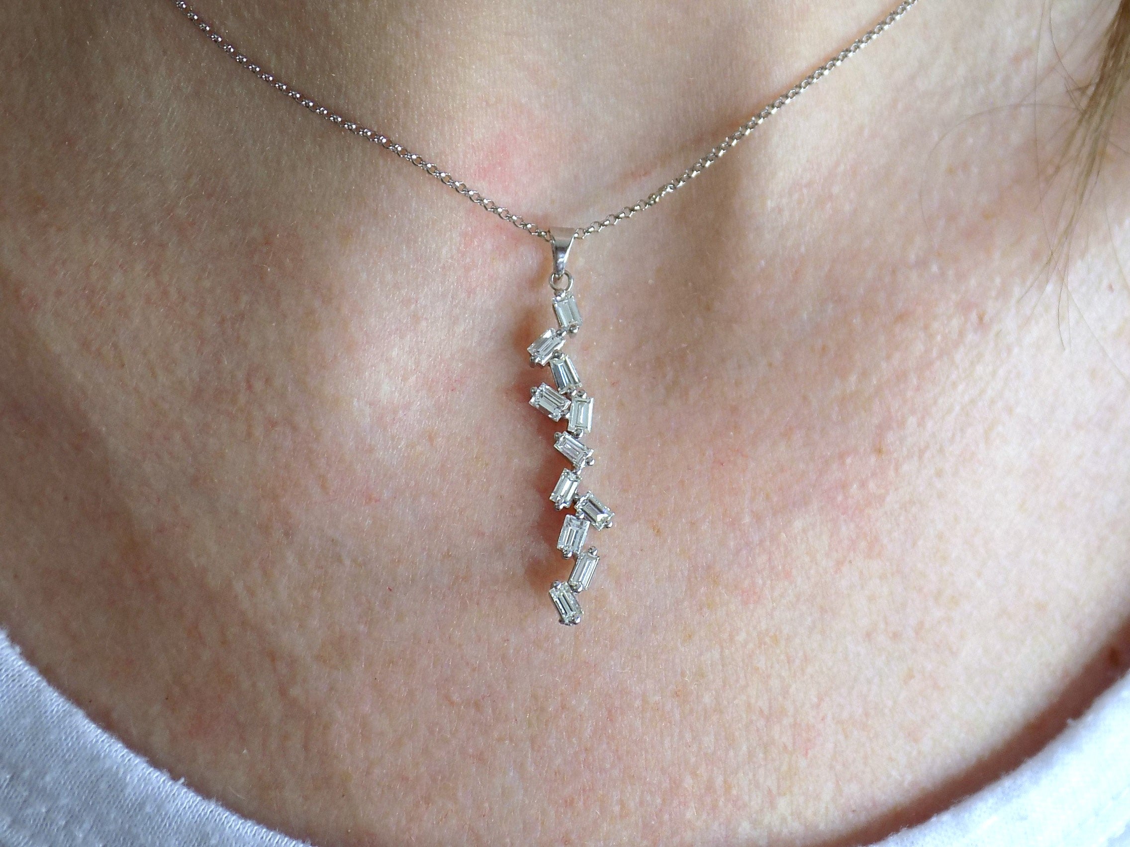 This is a custom made .91ct natural baguette diamond necklace in 18K white gold on a ladies neck with a white shirt.