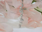 This is a custom made .91ct natural baguette diamond necklace in 18K white gold with a pink floral background.