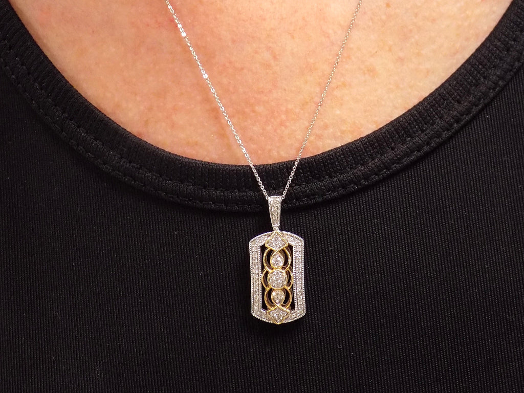 This is a .33ct natural diamond pendant that is a fiigree style in 2-tone white and yellow gold on a ladies neck with a black shirt.