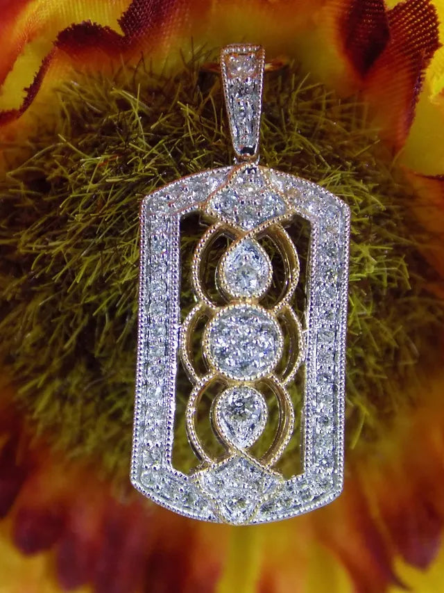This is a .33ct natural diamond pendant that is a fiigree style in 2-tone white and yellow gold with a colorful background.