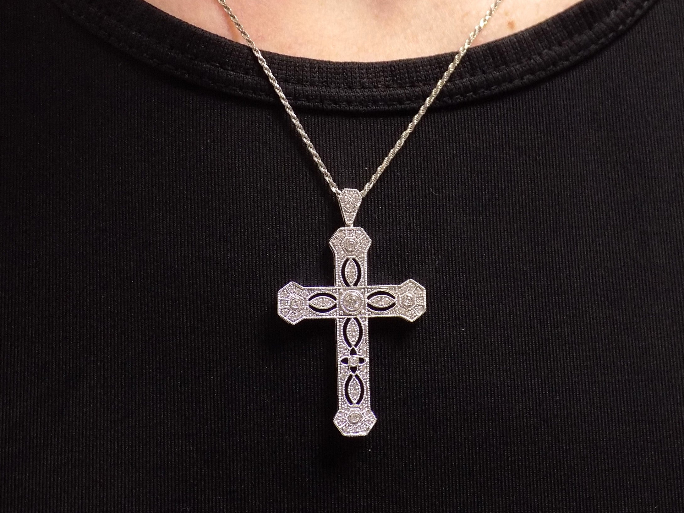 This is a .50ct natural diamond cross pendant with a very Victorian look in 10K white gold on a ladies neck with black shirt.
