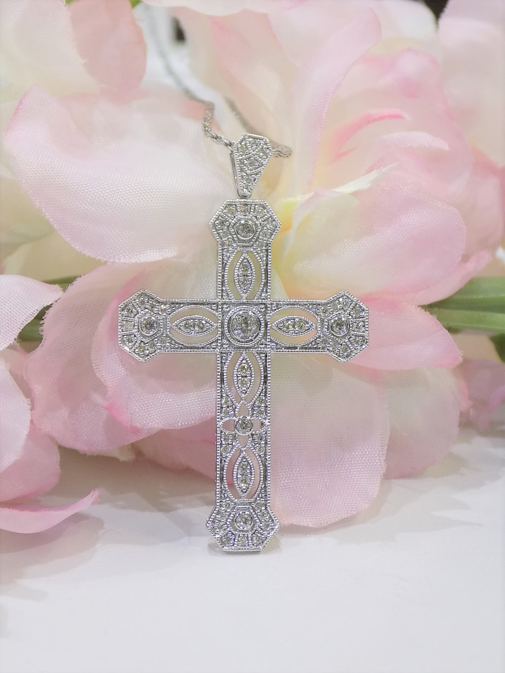 This is a .50ct natural diamond cross pendant with a very Victorian look in 10K white gold with a pink floral background.