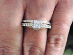 This is a halo style women's 2-piece wedding set including the engagement ring and matching band with princess cut center weighing .88ct total in white gold with rose accents shown on woman's finger.