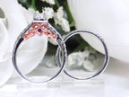 This is a side view of a halo style women's 2-piece wedding set including the engagement ring and matching band with princess cut center weighing .88ct total in white gold with rose accents shown with white background.