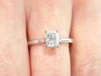 This is a women's 1.00ct natural radiant cut diamond solitaire ring in white gold shown on a woman's finger.