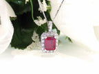 This is a women's pendant 3.65ct natural enhanced emerald cut ruby center surrounded by 1.56ct total weight in natural round diamond accents in 14K white gold.
