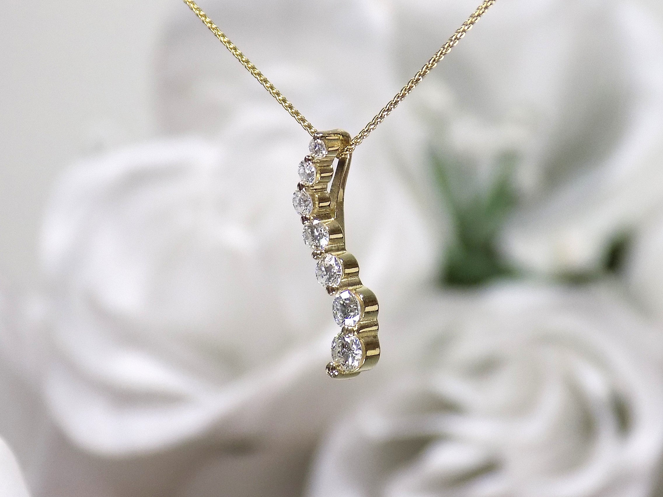 This is a side view of a vintage natural diamond journey style necklace in yellow gold.