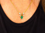 This is a women's necklace with a natural 1.00ct oval emerald and 1.00ct total weight natural marquise and round diamonds in 14K yellow gold on a women's neck.