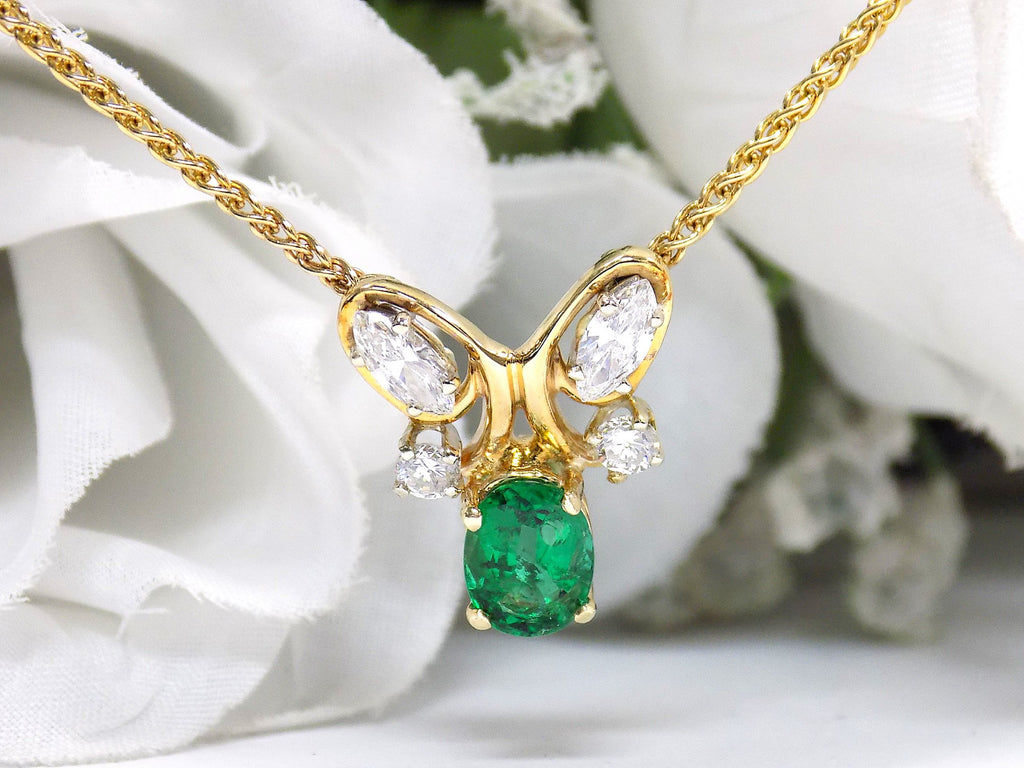 This is a women's necklace with a natural 1.00ct oval emerald and 1.00ct total weight natural marquise and round diamonds in 14K yellow gold with a white floral background.