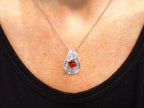 This is a vintage Victorian style women's oval (pigeon blood) natural 1.05ct ruby with .15ct natural round diamond accents in platinum on a women's neck with black shirt.