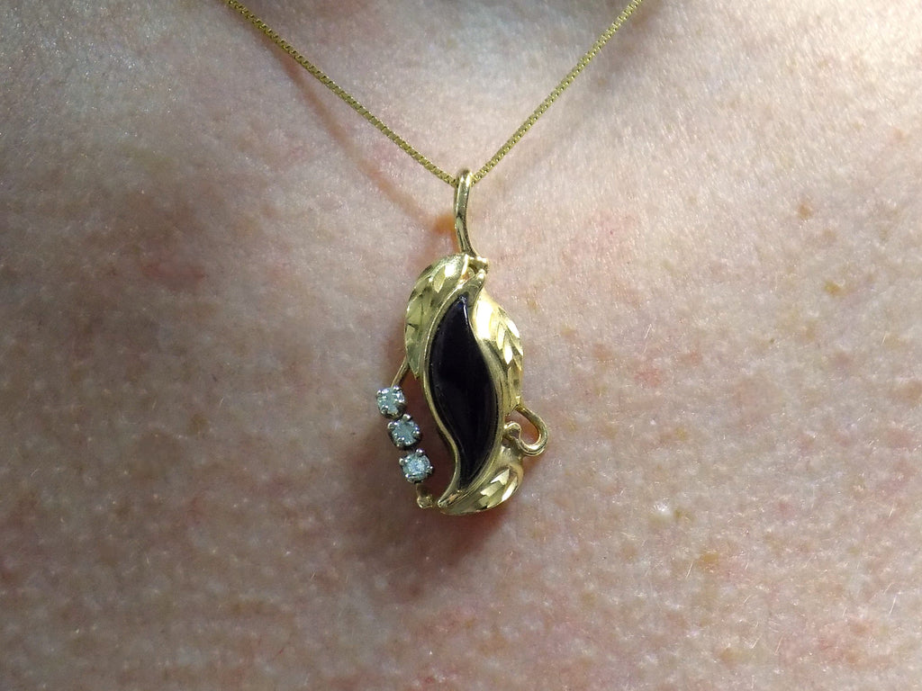 This is a genuine black onyx and diamond pendant or necklace in yellow gold shown on a woman's neck.
