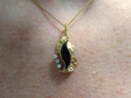 This is a genuine black onyx and diamond pendant or necklace in yellow gold shown on a woman's neck.