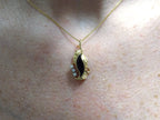 This is a genuine black onyx and diamond pendant or necklace in yellow gold shown on a woman's neck.
