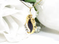 This is a genuine black onyx and diamond pendant or necklace in yellow gold with white flowery background.