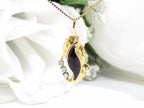 This is a genuine black onyx and diamond pendant or necklace in yellow gold with white flowery background.