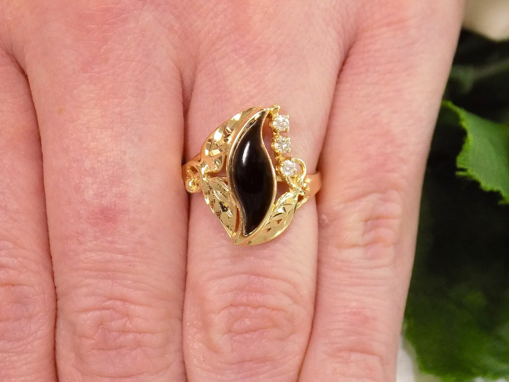 This is a genuine black onyx and diamond ring in yellow gold from our estate collection in like NEW condition shown on a woman's finger.