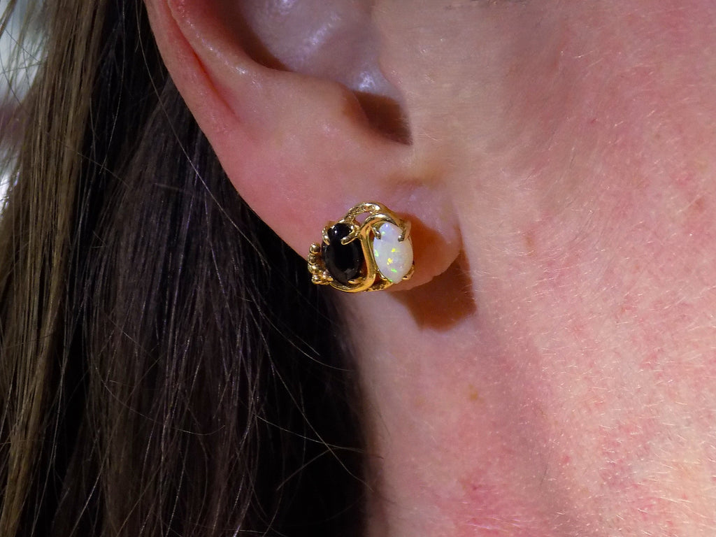 This is a pair of genuine opal and black onyx earrings in yellow gold shown in woman's ears.