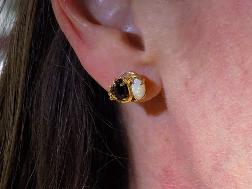 This is a pair of genuine opal and black onyx earrings in yellow gold shown in woman's ears.