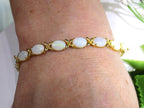 This is a genuine opal tennis bracelet in yellow gold from our estate collection in like new condition shown on a woman's wrist.