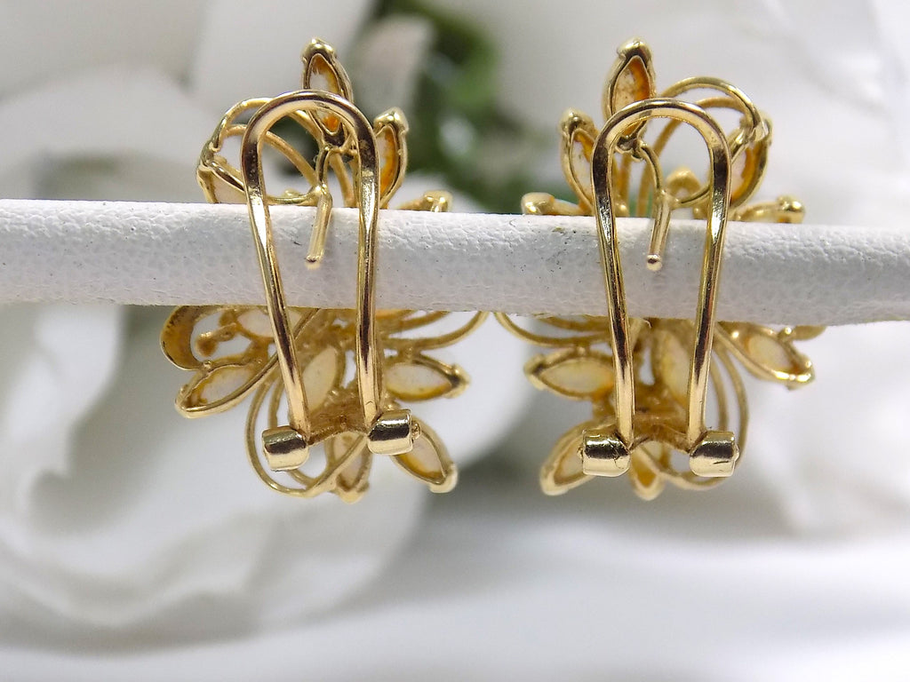 These are a pair of genuine marquise shape opal cluster earrings shown from the back highlighting the omega style backs in yellow gold shown on white flower background.