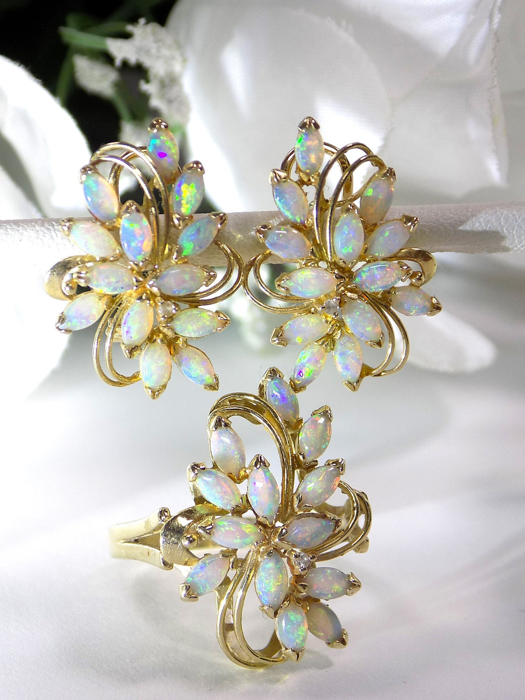 This is a set of genuine opal earrings and matching ring in yellow gold shown with a white flowery background.