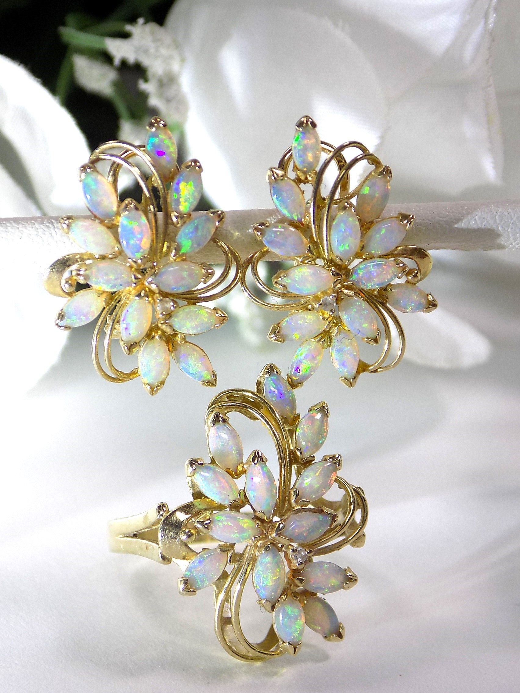 This is a set of genuine opal earrings and matching ring in yellow gold shown with a white flowery background.