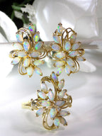 This shows a pair of natural opal earrings with a matching opal ring in yellow gold with white background.