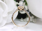 This is a side view of a oval shape diamond engagement ring in yellow gold with white gold prongs and a white background.