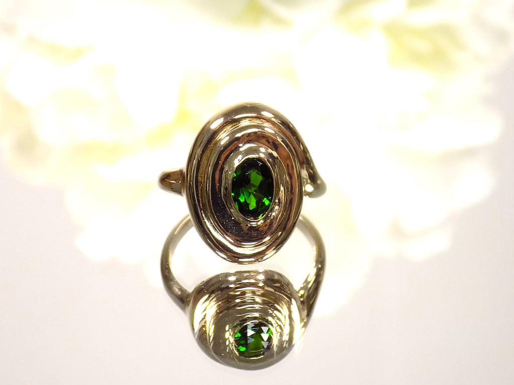 This is a women's estate ring with a .90ct oval green colored Tsavorite set in 14K yellow gold with a white floral background.