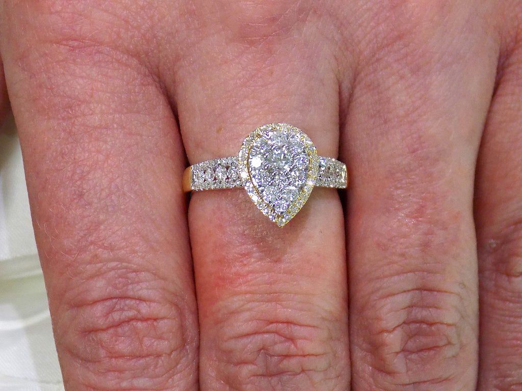 This is a .75ct total weight pear shape natural diamond cluster ring in two tone white and yellow gold on a ladies finger.
