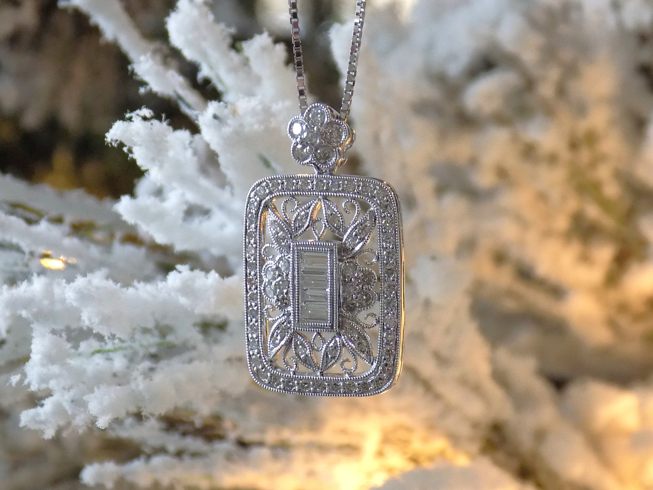 This is a Victorian style pendant with 1.00ct total weight round and baguette diamonds set in 900 platinum with a white snowy looking background.