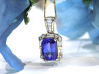 This is a women's 4.90ct natural high-end rectangular cushion cut tanzanite pendant surrounded by .75ct natural baguette and round diamond accents in 14K yellow gold with a floral background.