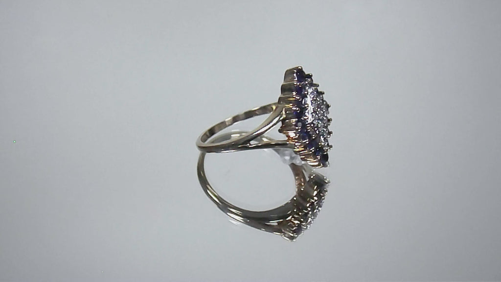 This is a video of a refurbished vintage genuine sapphire & diamond cluster ring in yellow gold shown turning slowly on mirrored background.