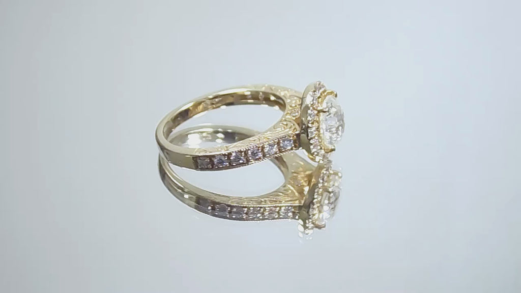 This is video of a halo style 2.17ct total weight natural round diamond ring with a 1.52ct center diamond in yellow gold shown turning slowly on a mirrored background.