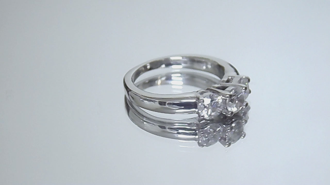 This is a video of a 3-stone style natural .90ct total weight round diamond ring in white gold turning slowly on a mirrored backgound.