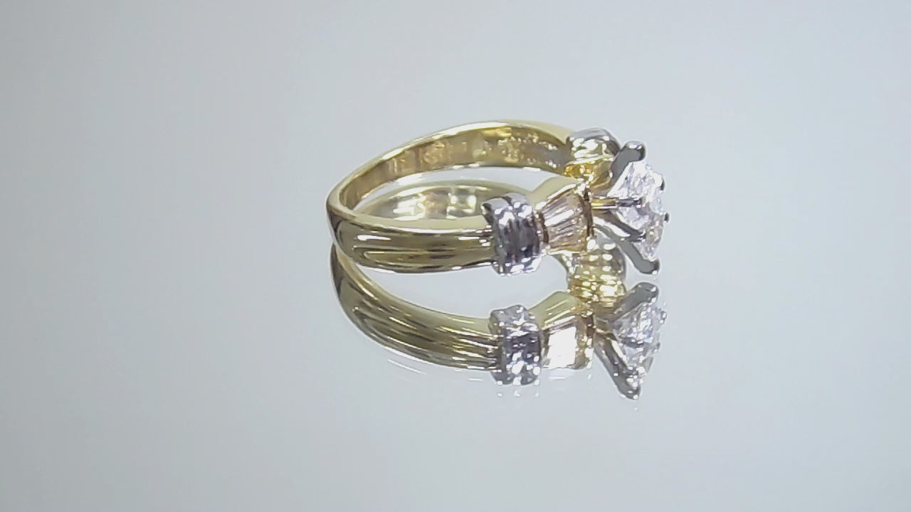 This is a a video of a .80ct total weight natural diamond ring baguette diamond accents in 2-tone 18K yellow gold and platinum shown rotating on a mirrored background.