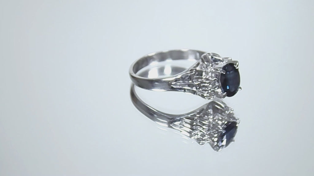 This is a video of a women's vintage pre-world war II genuine oval shape sapphire and natural diamond ring 1.36ct total weight in platinum restored to showcase condition shown rotating on a mirrored background.