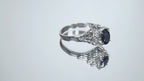 This is a video of a women's vintage pre-world war II genuine oval shape sapphire and natural diamond ring 1.36ct total weight in platinum restored to showcase condition shown rotating on a mirrored background.