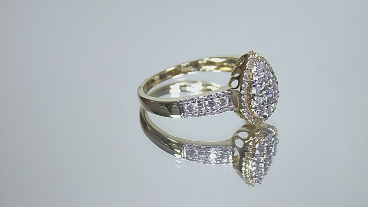 This is a .75ct total weight pear shape natural diamond cluster ring in two tone white and yellow gold rotating in a video on a mirrored background.