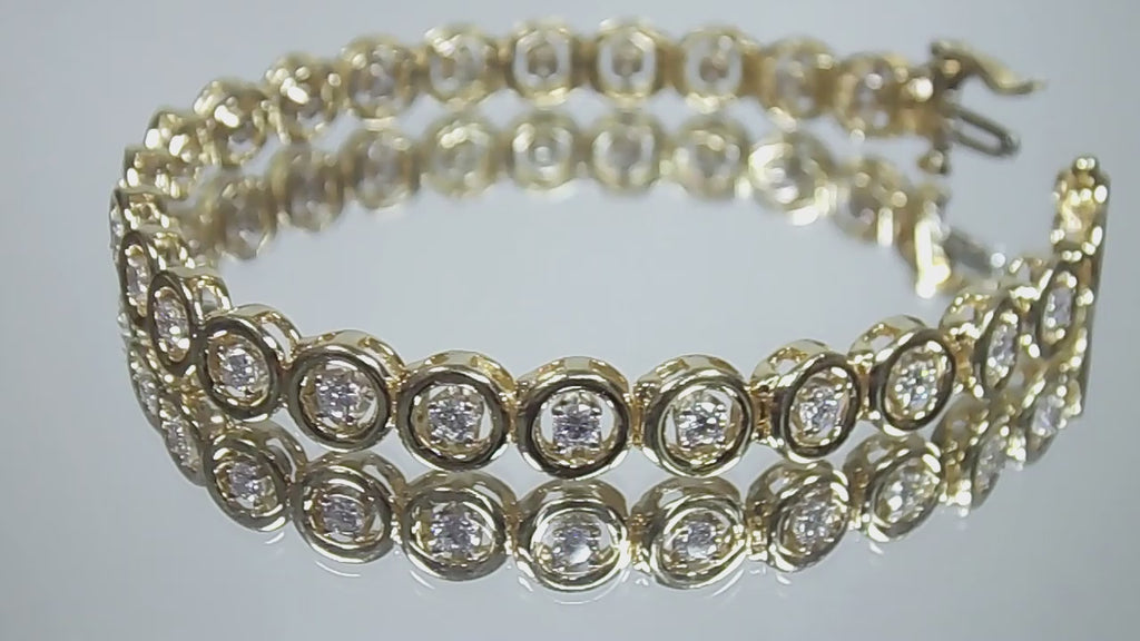 This is a 2.00ct total weight diamond bracelet in 14K yellow gold on a mirrored background rotating in a video.