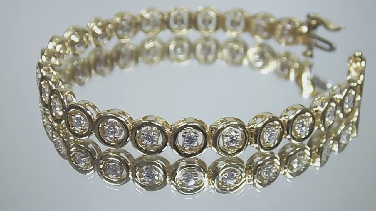 This is a 2.00ct total weight diamond bracelet in 14K yellow gold on a mirrored background rotating in a video.