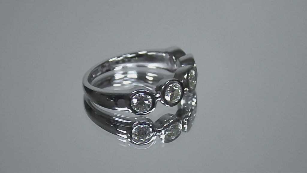 This is a 5 stone bezel set natural round diamond band in 14K white gold rotating in a video on a mirrored background.