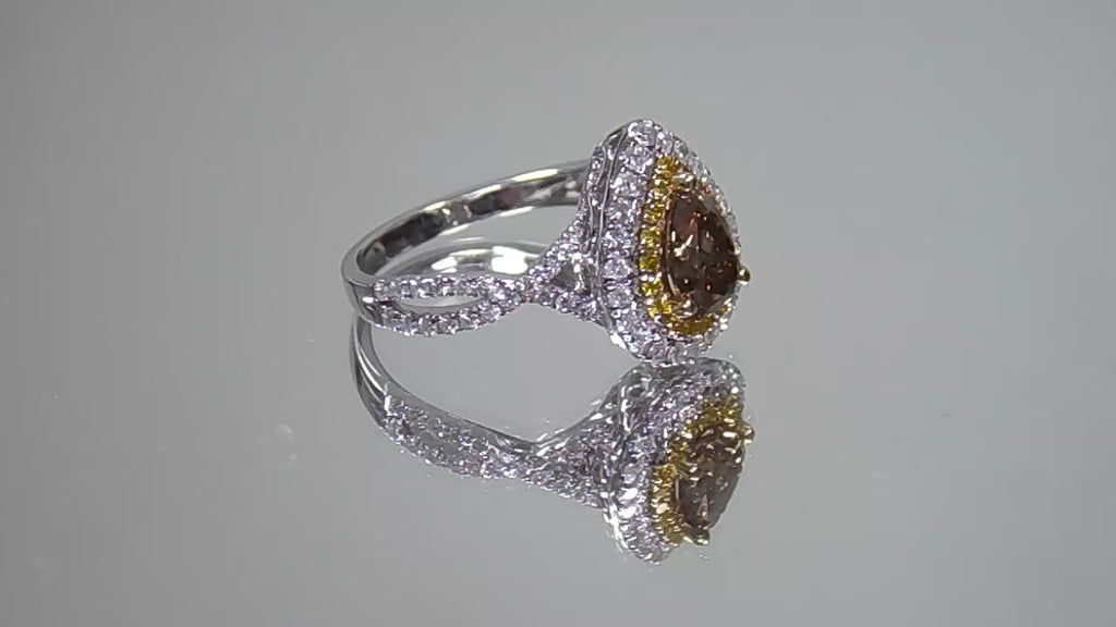 This is a video of a 1.69ct total weight genuine natural pear shape chocolate diamond ring with canary yellow and white diamond accents in white gold shown rotating slowly on a mirrored background.