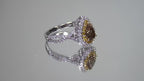 This is a video of a 1.69ct total weight genuine natural pear shape chocolate diamond ring with canary yellow and white diamond accents in white gold shown rotating slowly on a mirrored background.