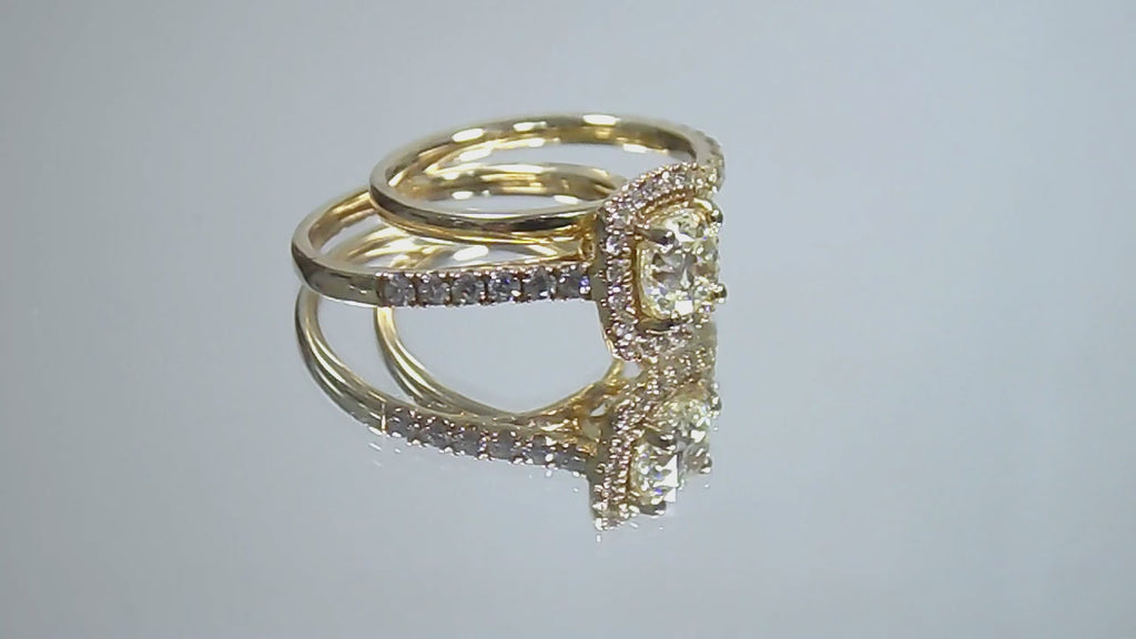 This is a video of a halo style 2-piece wedding set which includes the engagement ring and a matching band for a total of 1.77ct in natural round diamonds shown rotating on a mirrored background.