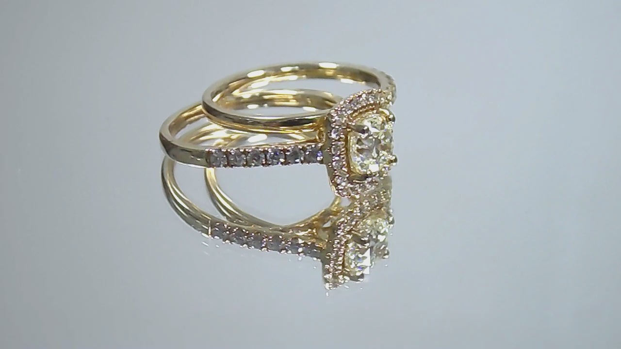 This is a video of a halo style 2-piece wedding set which includes the engagement ring and a matching band for a total of 1.77ct in natural round diamonds shown rotating on a mirrored background.