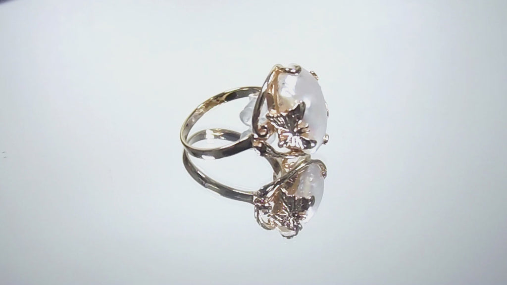 This is a video of a genuine freshwater pearl ring in yellow gold shown turning slowly on a mirrored background.