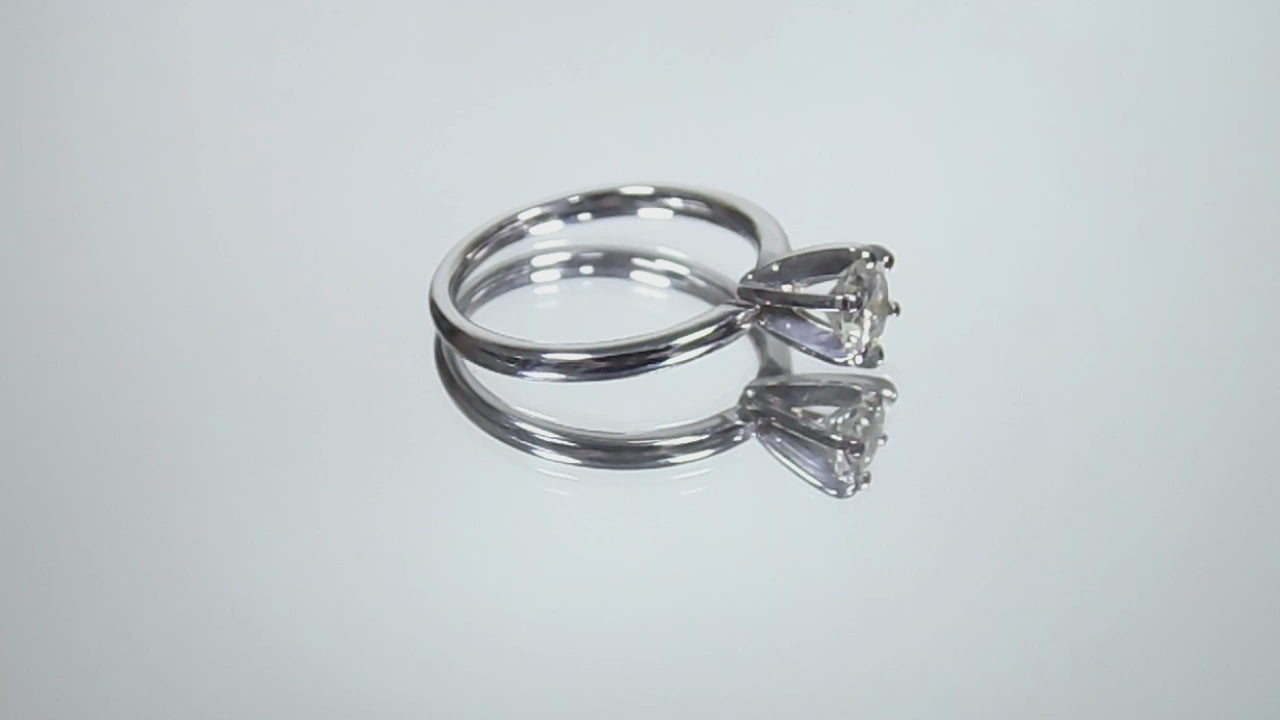 The is video of a natural .60ct round brilliant diamond solitaire engagement ring in white gold shown turning slowly on mirrored background.