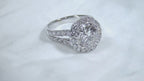 This is a video of a 3.55ct total weight natural diamond ring with a 2.05ct natural round diamond center in white gold shown rotating slowly on a mirrored white background.